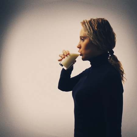 Part of series. Portrait of young woman drinking milk in glass, copy spaceの写真素材