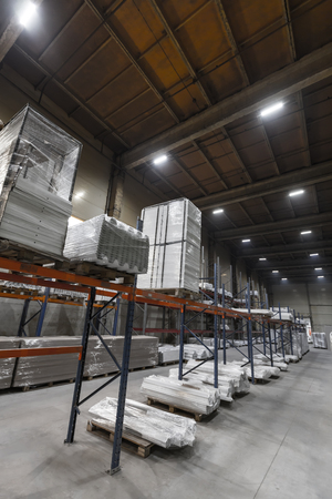 Generic warehouse industrial interior with palettes stacked on shelves. Wide angle perspective viewの写真素材
