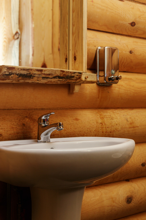 A traditional Russian wooden construction with logs, round bars on the wall of the house with modern ceramic wash sinkの写真素材