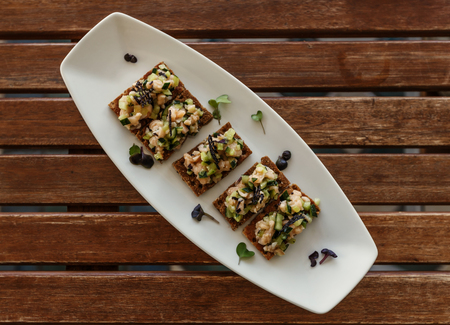 Crispy flatbread sandwiches with salad seasoning served on white ceramic oval plate