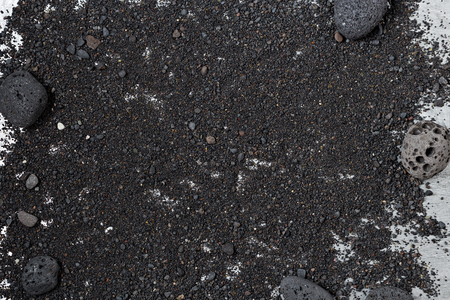 Black volcanic sand background with round lava rocksの写真素材