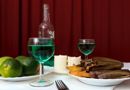 Horisontal view of tropical dinner with carambola, passionfruit, razor clam shells, green wine and two candlesの写真素材