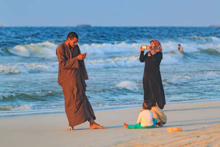 EL AGAMY, ALEXANDRIA, EGYPT - CIRCA OCTOBER 2014 - undefined egyptian family taking pictures of each-other by smartphones by the Mediterrenian sea at sunsetのeditorial素材