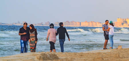 EL AGAMY, ALEXANDRIA, EGYPT - CIRCA OCTOBER 2014 - undefined Egyptian couples take a walk by the sea at sunsetのeditorial素材