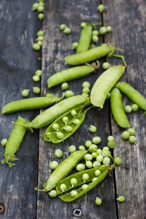 Pods of green peas and pea on a dark wooden surface, top viewの写真素材