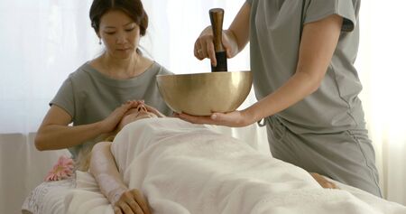ladies in grey costumes make massage and play tibetan bowlの写真素材