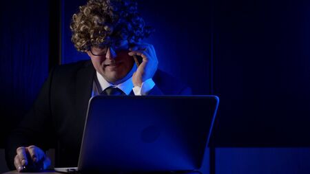 comic adult man dressed in business suit and funny curly wig on head, calling working in officeの写真素材