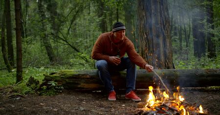 handsome guy moves branches with stick and drinks beerの写真素材