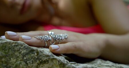 Close-up of the hand of a young girl with an unusual ring on it, she holds her on the stones.