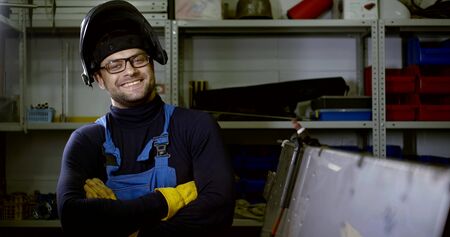 handyman in glasses and welding mask stands in workshopの写真素材