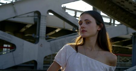 alone sad woman is leaning handrail of big bridge in town in sunny dayの写真素材