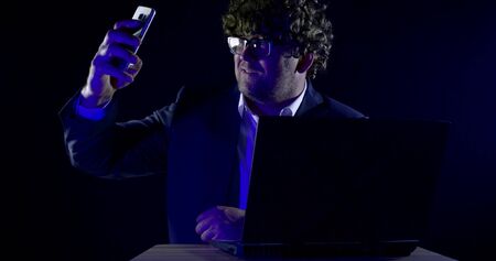 Close-up portrait of a curly-haired man in glasses and a shirt, jacket he sits at a laptop on a...