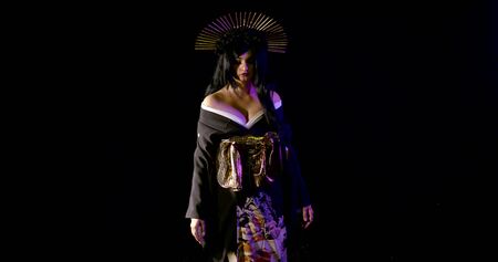 religion concept, beautiful makeup for Halloween. young pretty girl in a Japanese kimono and a crown of gold spikes on a dark backgroundの写真素材