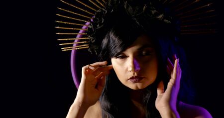 Close-up portrait of a girl in the image of the virgin Mary on a black background with neon lights....