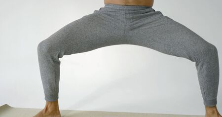muscular man is standing with lifted hands, tensing muscles of body and meditating with closed eyes