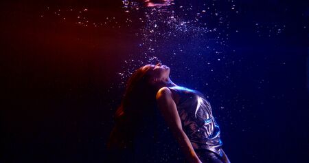 woman is swimming underwater and moving up to surface, subaquatic shotの写真素材