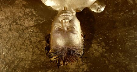 woman with painted gold skin and hair takes bath slow motion