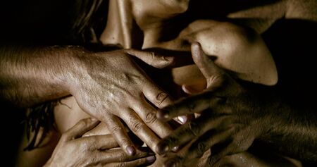 beautiful mature couple bodies covered with golden skin paint being intimate on black background extreme closeup slow motionの写真素材