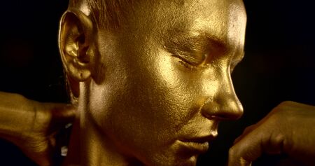 Close-up portrait of a gentle girl, she is in the Studio on a black background, she has a Golden...
