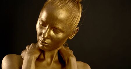 beautiful actress with golden body and face art, posing in studio