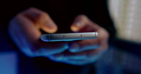 close-up of the end part of the smartphone. the man holds the phone in front of him and moves his...
