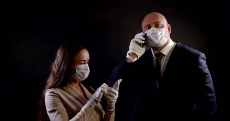 man and woman dressed face masks and gloves, using mobile phonesの写真素材