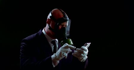 businessman with protection from coronavirus, respirator and gloves is reading news by smartphone