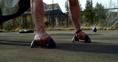 sporty man is doing push-ups outdoors, training alone in park area in daytime