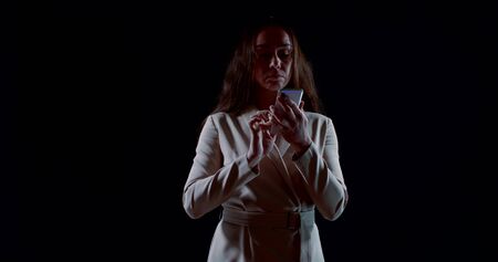 businesswoman is typing message at smartphone, rotating figure in darknessの写真素材