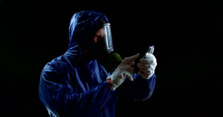 A man in a protective gas mask. A person clicks on the touch screen of a phone wearing a chemical...