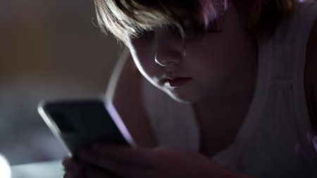child girl is using mobile phone, playing video games in internet at night, social net addiction