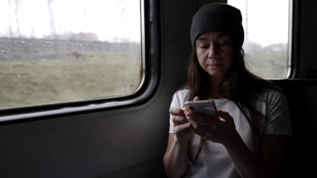 woman is travelling by suburban train, using smartphone, chatting in social nets