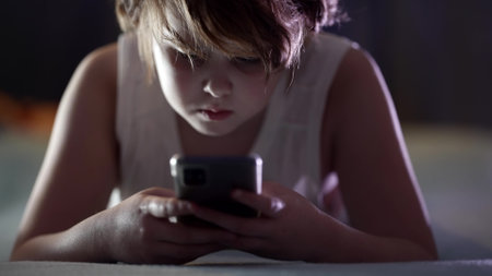 child is using smartphone at night, playing video games, surfing internet