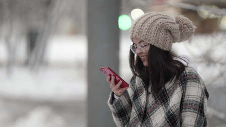 joyful teen girl with smartphone on city street at winter day, internet and social net addiction of youthの写真素材