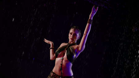 sexy arabian dancer woman is posing under rain at night, female figure in darknessの写真素材