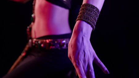 traditional belly dance, woman is wearing arabian or indian suit is moving abdomen in darkness