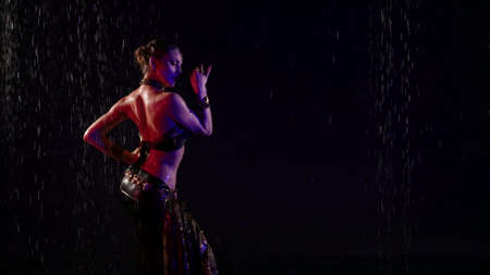 figure of exotic oriental dancer woman in darkness under rain, lady is wearing long skirtの写真素材