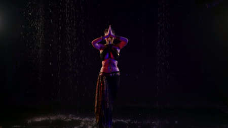 belly dance under rain at night, sexy female dancer is moving in darkness, full-length portraitの写真素材