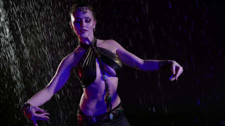 contemporary belly dancer lady is dancing under rain at night, woman is moving eroticallyの写真素材