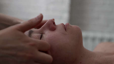 beautician is massaging face of adult woman, relaxing procedure for rest and rejuvenate, closeupの写真素材
