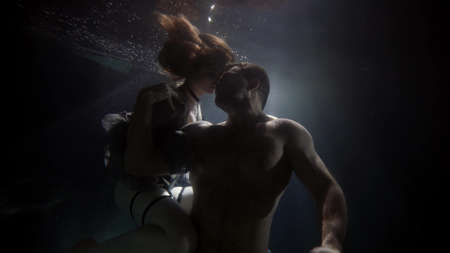 caresses of loving couple inside water of swimming pool, underwater shot, romantic and sexualityの写真素材