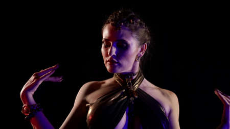 A close-up woman who is dancing an oriental belly dance in the studio, makes beautiful movements...
