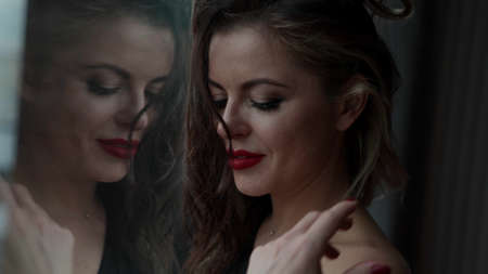 seductive sexy woman is playing with her long dark hair and flirting with cameraの写真素材