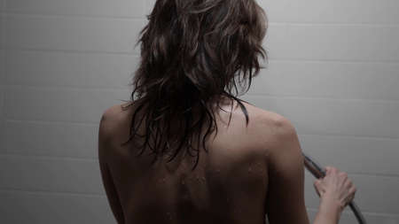 sexy woman is taking shower, pouring her naked body by water, rear view of female figureの写真素材