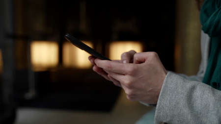 woman is using smartphone in cafe, closeup of hands with modern gadget, surfing internetの写真素材