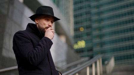 spy or undercover policeman is smoking cigarette outdoors in city and stalking someoneの写真素材