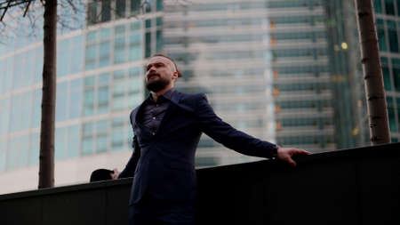 pensive and emotional man is standing alone on street in city, lonely human in urbanistic landscapeの写真素材