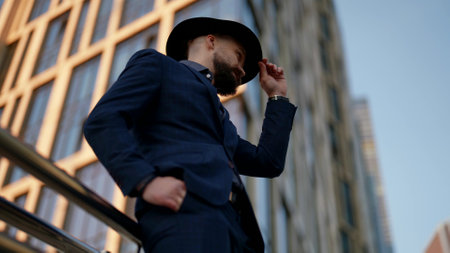 elegant man is waiting someone on city street in modern district, handsome guy with moustacheの写真素材