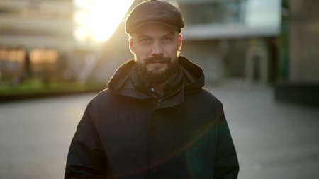 young man is looking kindly to camera, standing alone in urban landscape in morningの写真素材