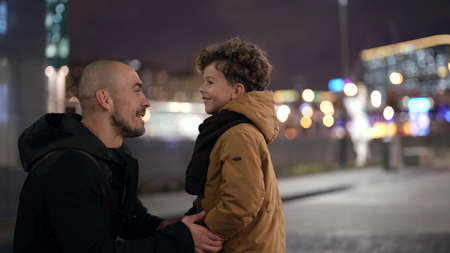 father and little son on city street in evening, adult man is communicating with little boyの写真素材